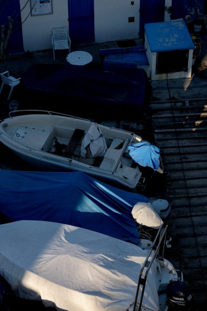 Boats covered with tarps at a dock.